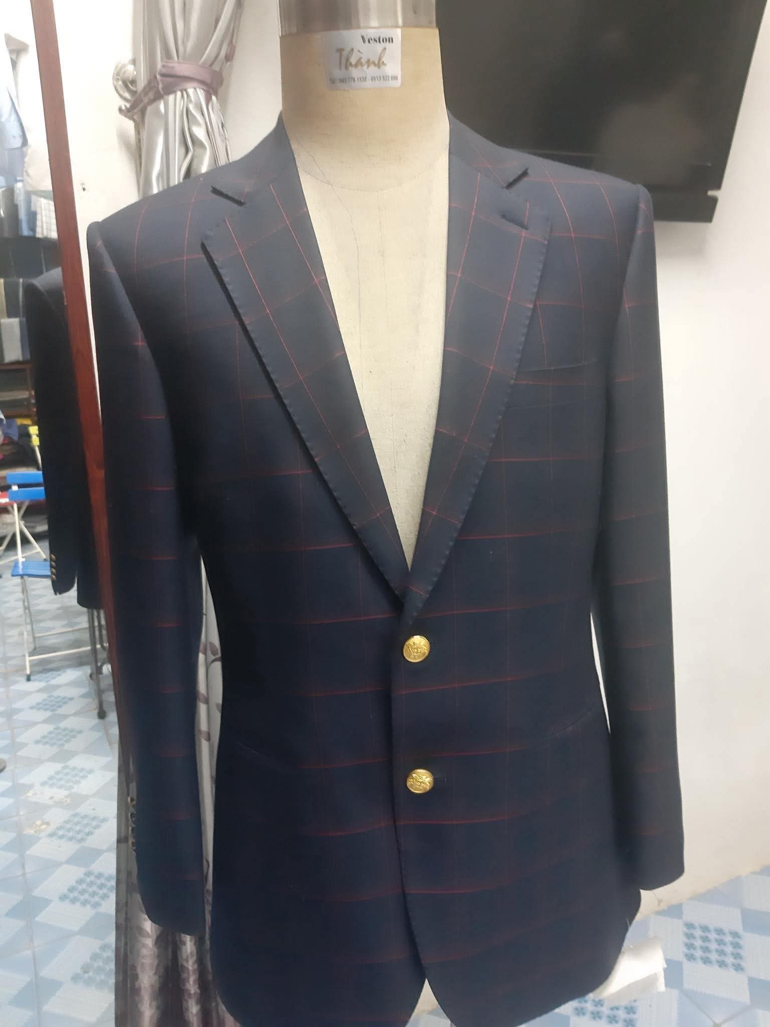 Áo vest xanh đậm kẻ ô với cúc vàng trên ma-nơ-canh